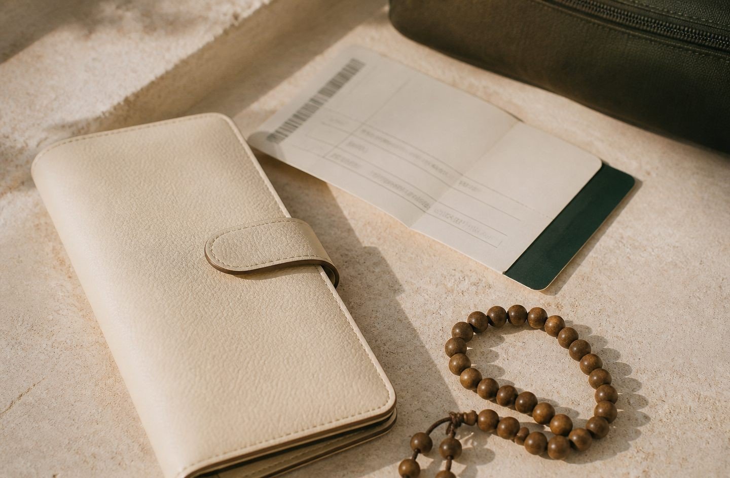 A travel wallet and prayer beads on pale stone